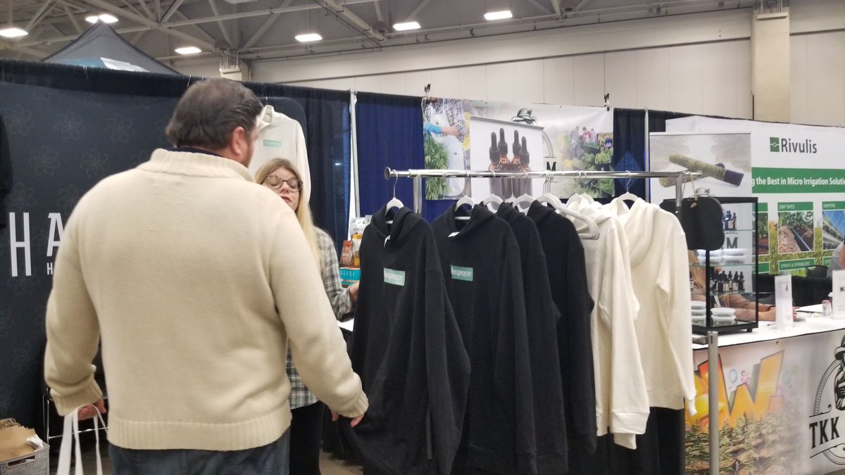 A woman shows off some hemp hoodies in a booth at the Texas Hemp Convention.