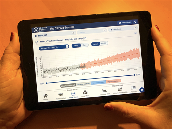 Hands hold a tablet with an image of a temperature graph for Moab, UT on it. 