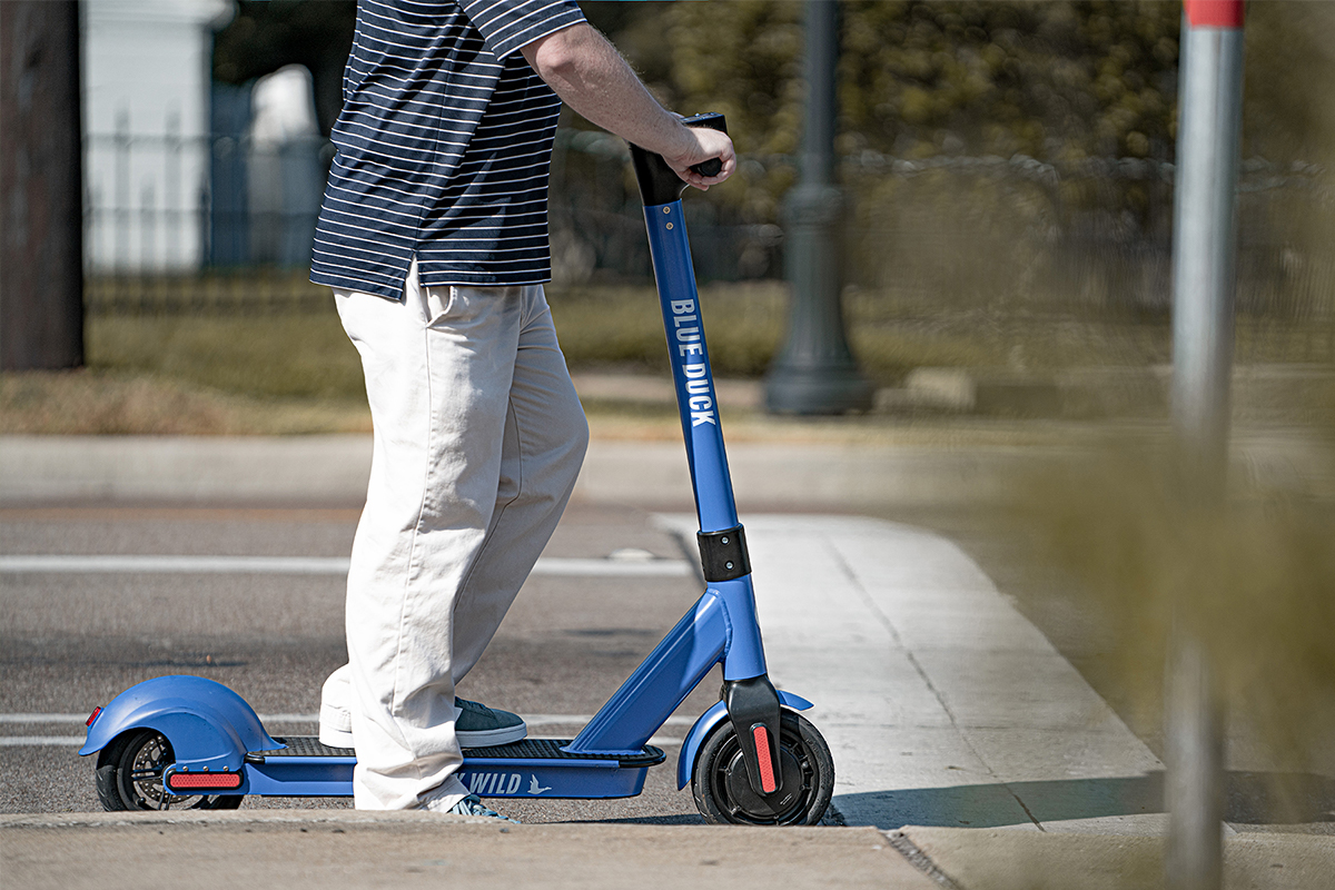 Man riding a blue electric scooter