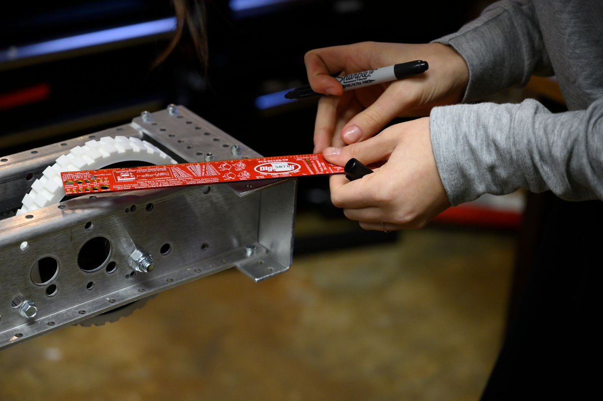 Detail photo of hands measuring part of a robot.