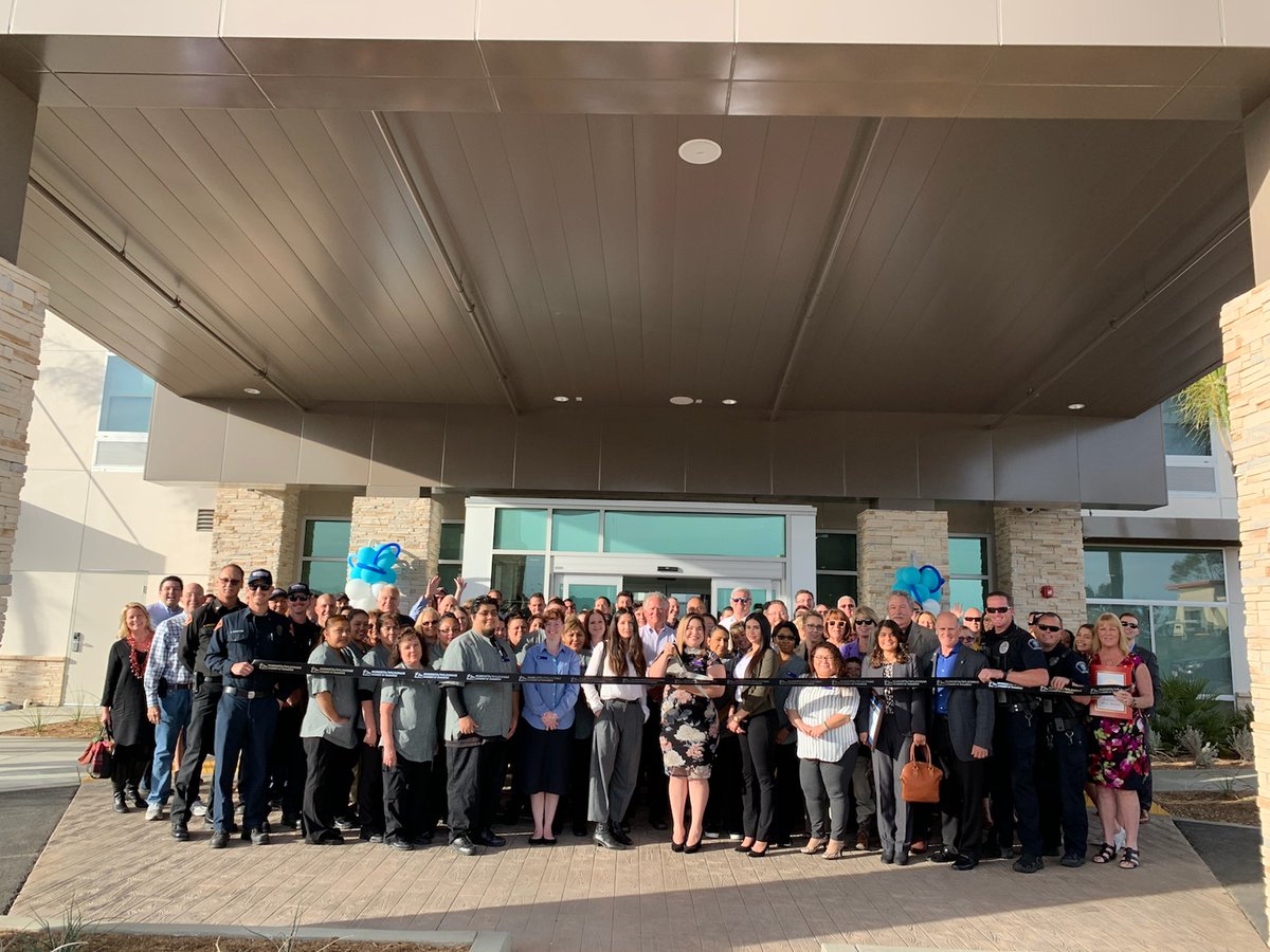 Group of people standing in front of a ribbon in front of a hotel.