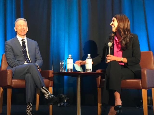 man and woman sitting on stage laughing