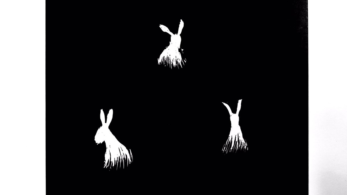 Scratchboard drawing of three white bunnies, hiding in the grass, on a black background.