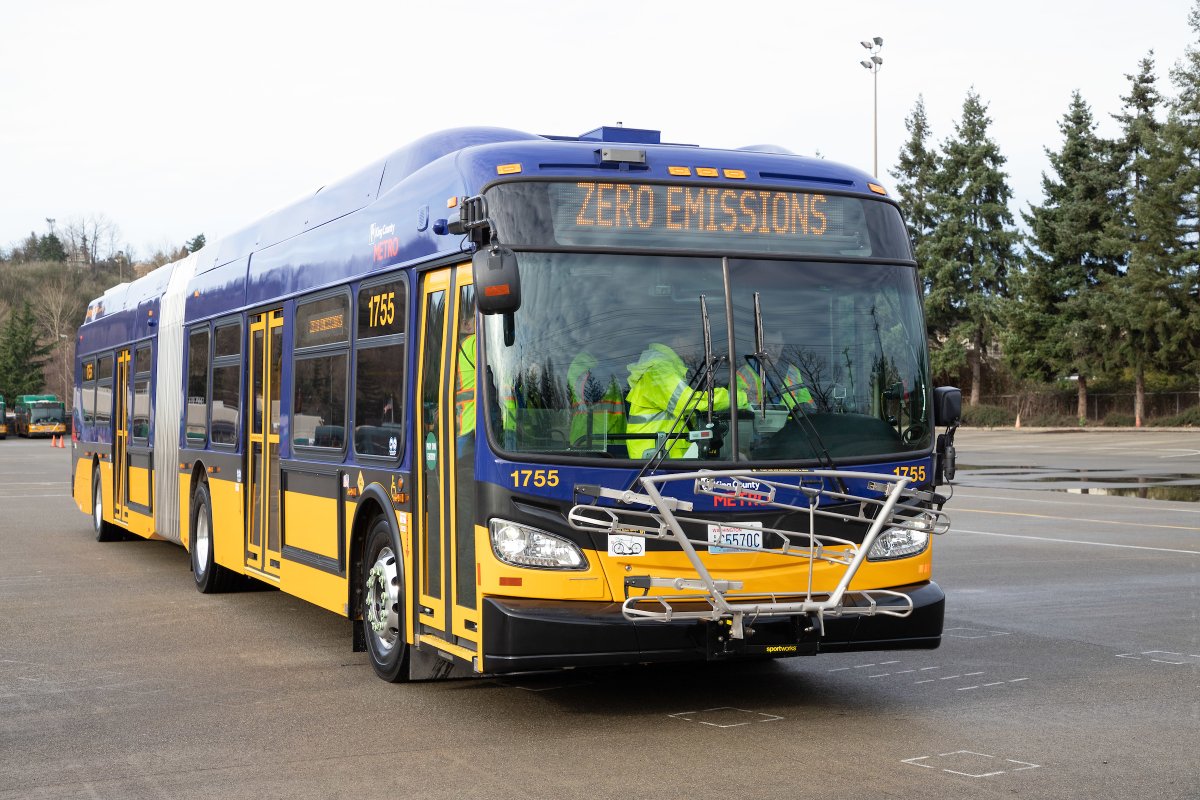 Battery electric 60-foot-long New Flyer bus with sign reading Zero Emissions