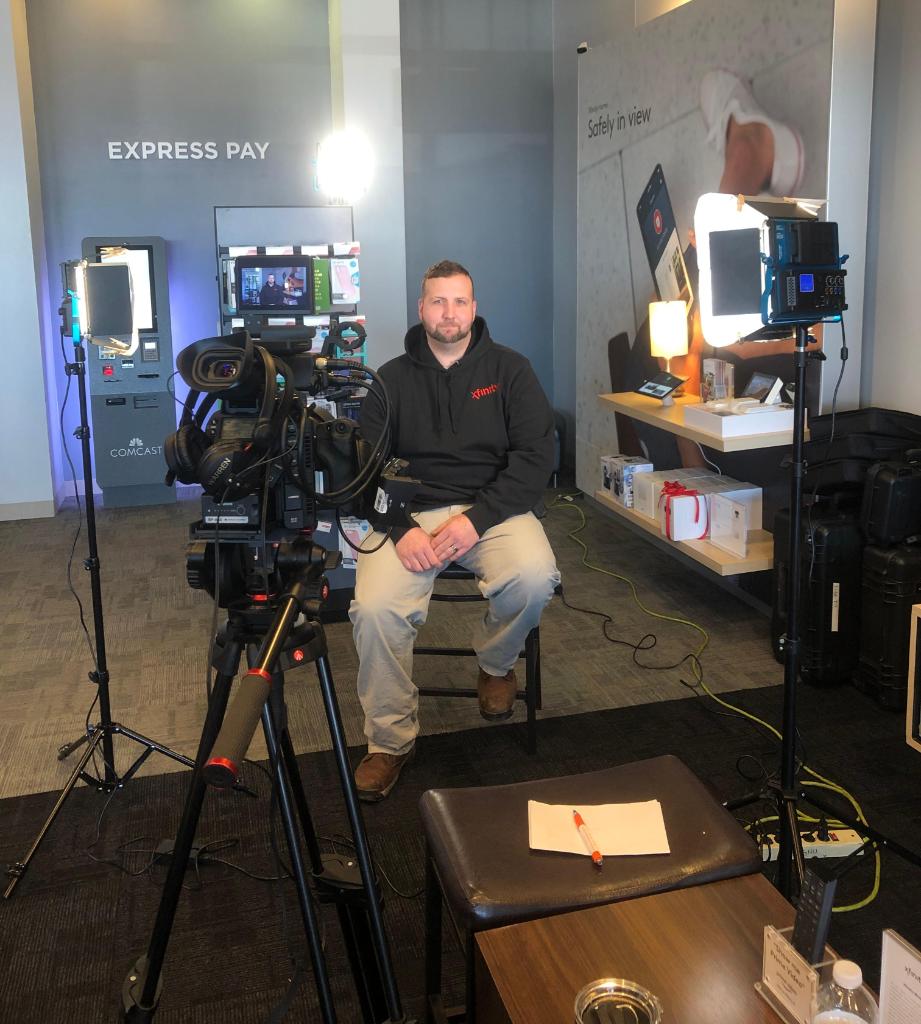 Man sitting in front of camera with lighting and camera cases visible