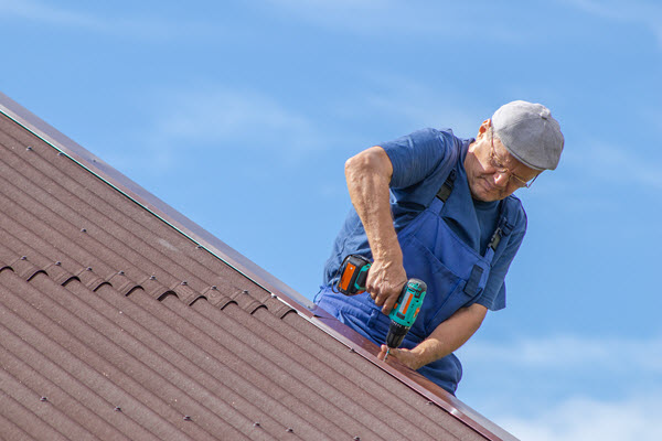 Older man installing roofing on a house