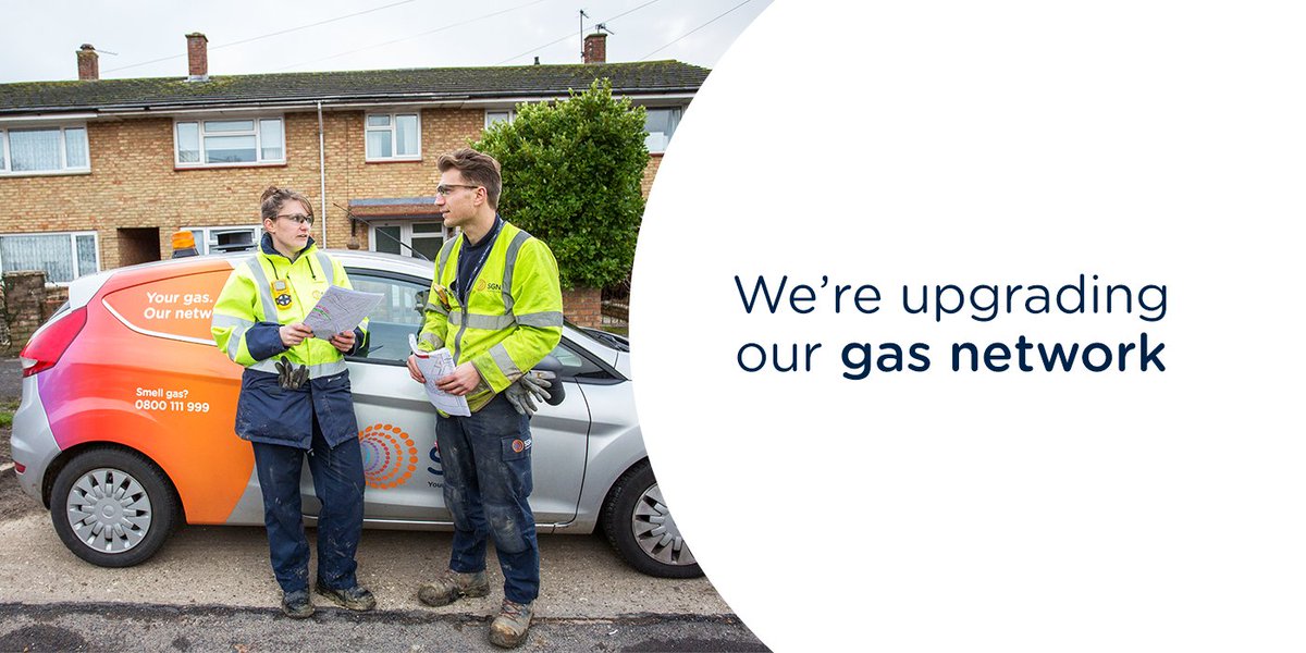Two gas engineers standing by their vehicle discussing their project.
