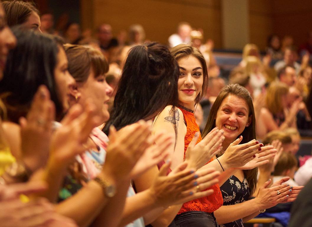 A group of people stood up clapping at an awards ceremony.