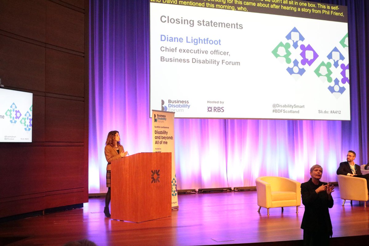 Diane Lightfoot on stage at Scottish conference. On the screen says Diane Lightfoot CEO Business Disability Forum