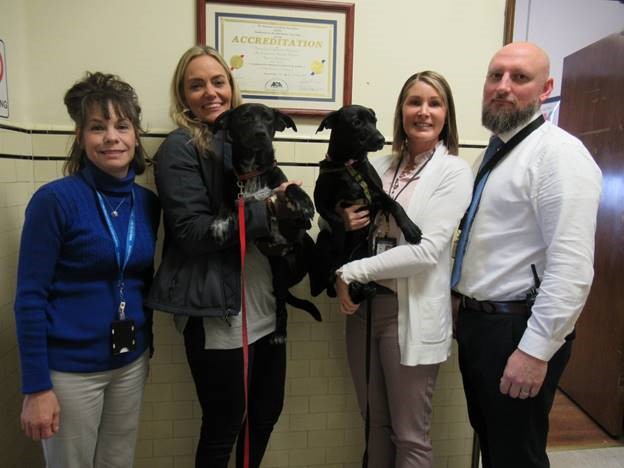 DOC employees holding two puppies