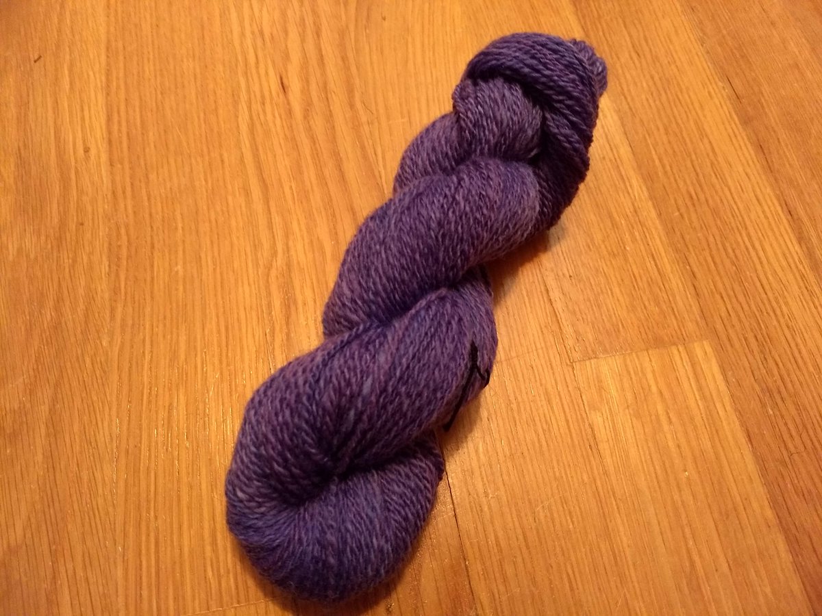 A skein of handspun yarn, neatly twisted back on itself. It is spun as a fairly consistent 2-ply fingering weight, and is dyed solid purple with minor variation throughout.