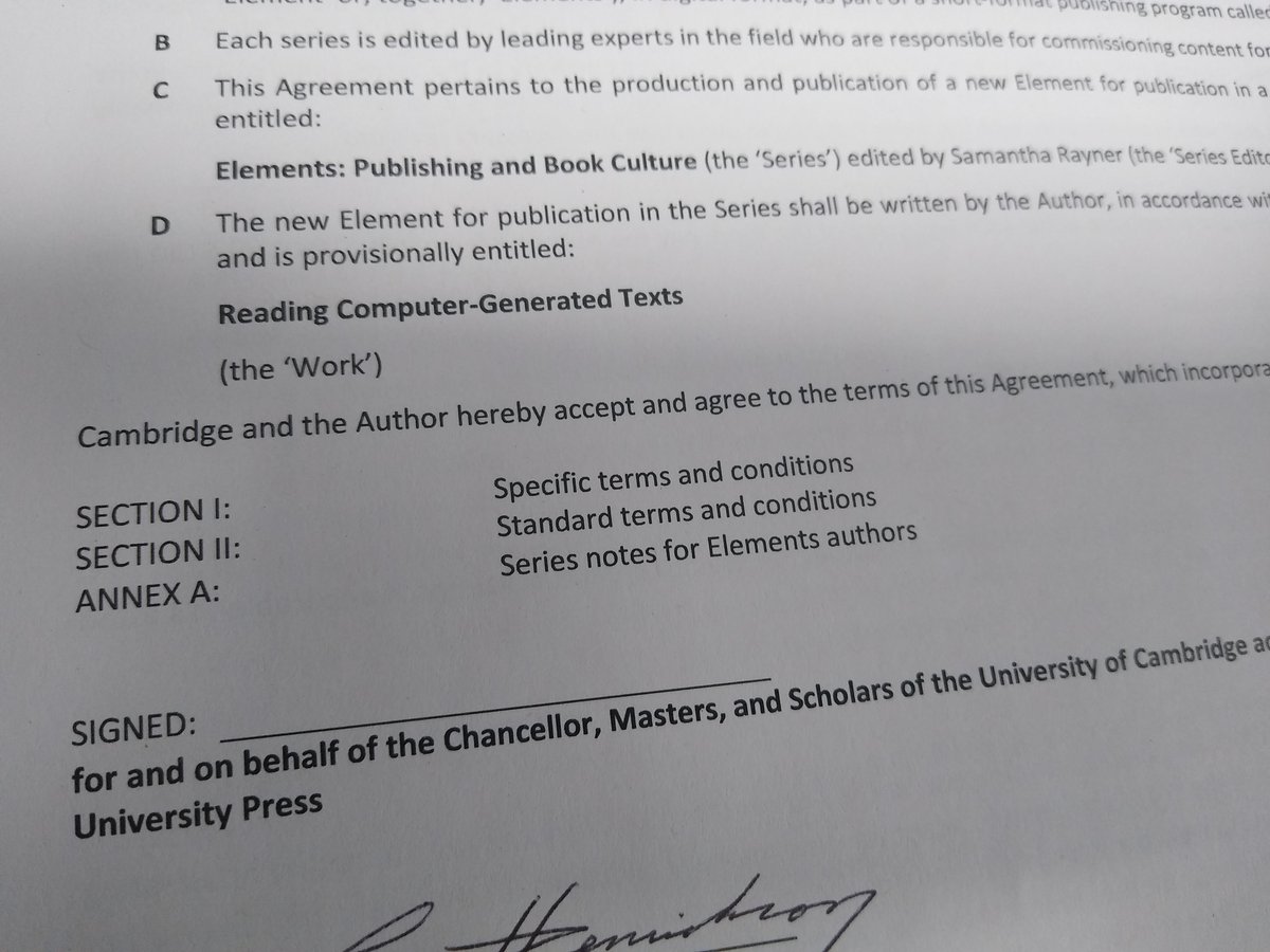A photograph of a signed publishing contract for a book called 'Reading Computer-Generated Texts'.