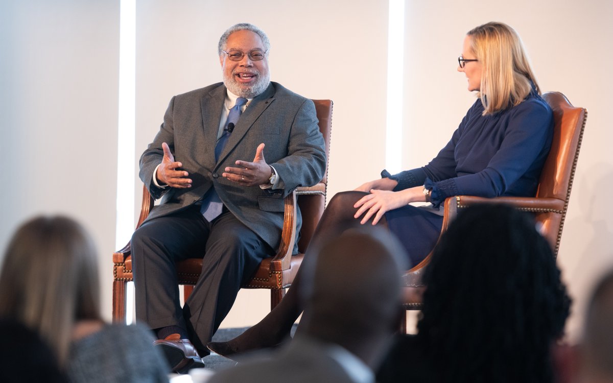 Two people seated on a stage in conversation.