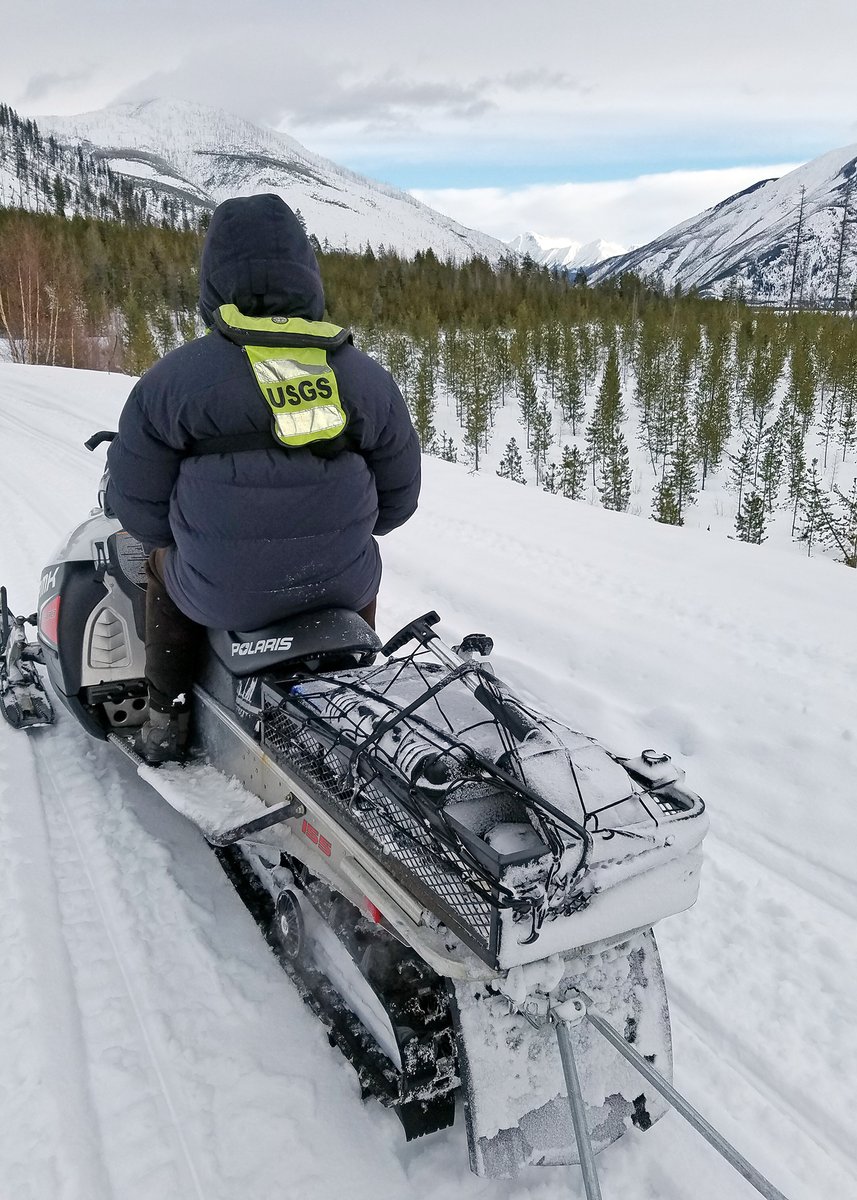 U.S. Geological Survey hydrologic technician Ryan Smith travels by snowmobile to collect data from USGS streamgages near Glacier National Park. (Dan Hess, U.S. Geological Survey. Public domain.)