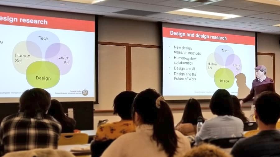 Professor Vincent Aleven stands in front right corner of a full classroom giving a presentation about our undergrad HCI programs