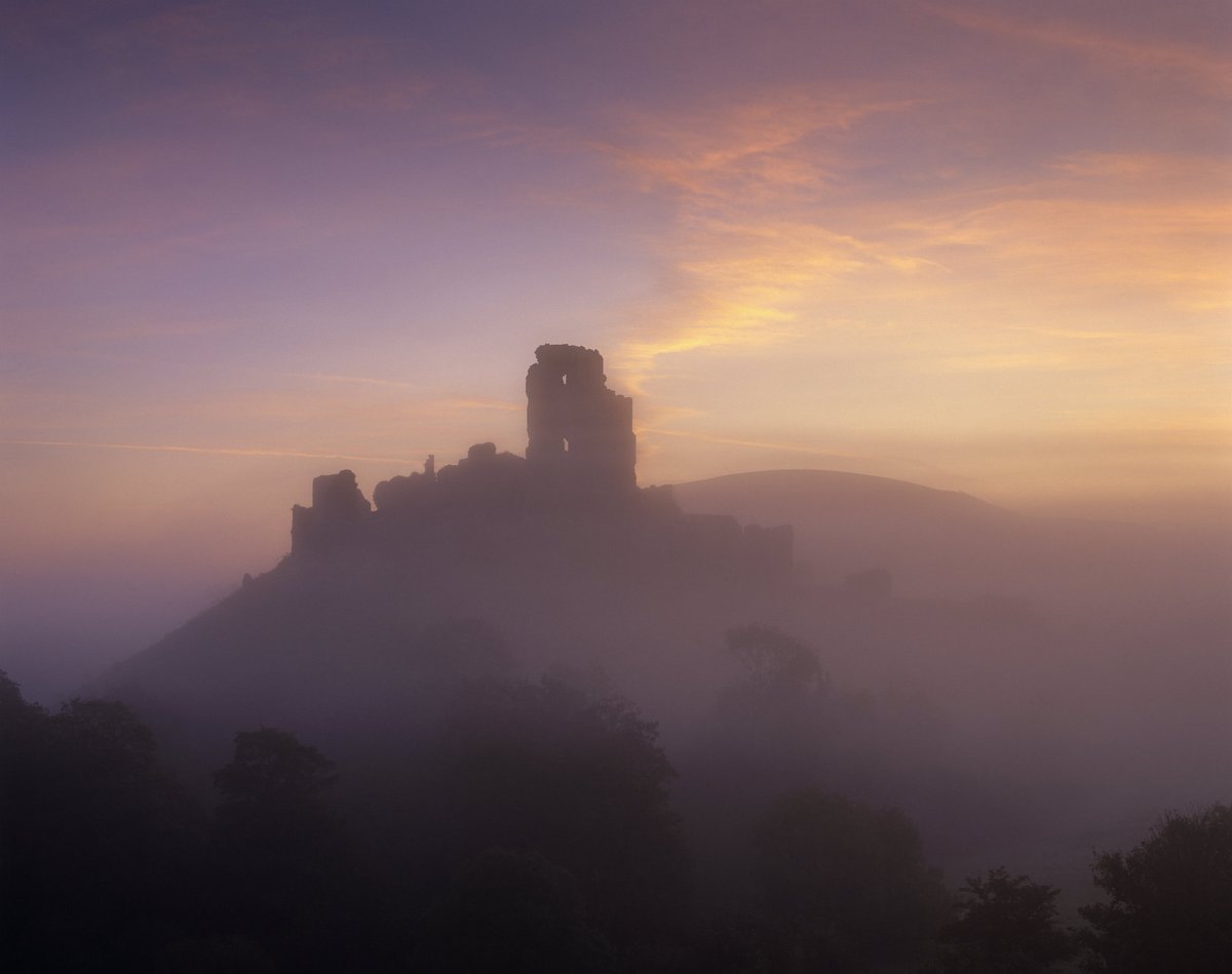 Silhouette of the ruins of Corfe Castle as seen through the mist.