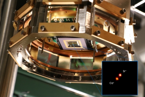 A cylindrical metal housing holding a ion-trap chip at it’s center.