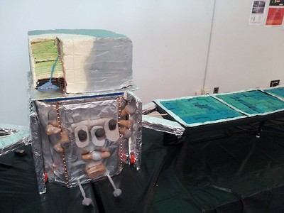1/4 scale model of the Fermi spacecraft - from cake. The solar cells are homemade, hand-cast hard candy wafers. They even included the electron-positron conversion tracks in the LAT (Large Area Telescope) on the top. Credit: Eric Winter