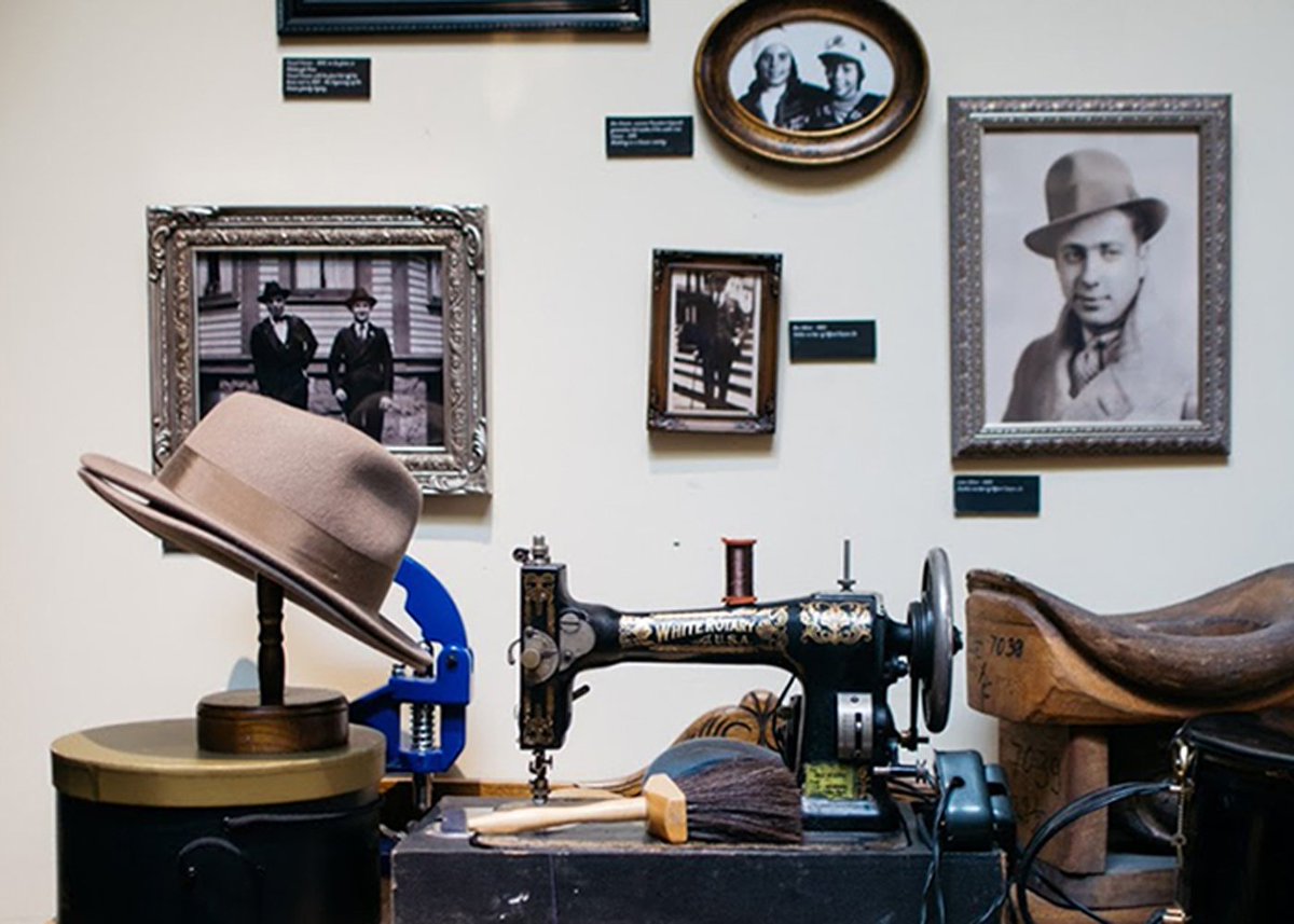 A collection of vintage artifacts sitting on a table. Includes: photos, sewing machine, saddle, and a hat