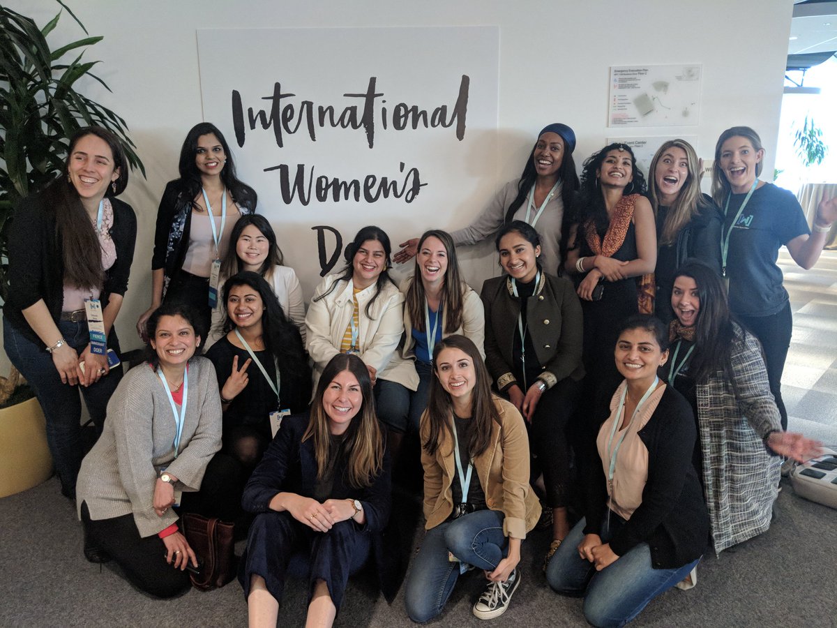 Googlers and summit attendees take a group photo around an "International Women's Day" sign.