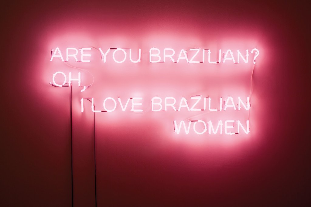 A pink neon sign reading, "Are you Brazilian? Oh, I love Brazilian women."