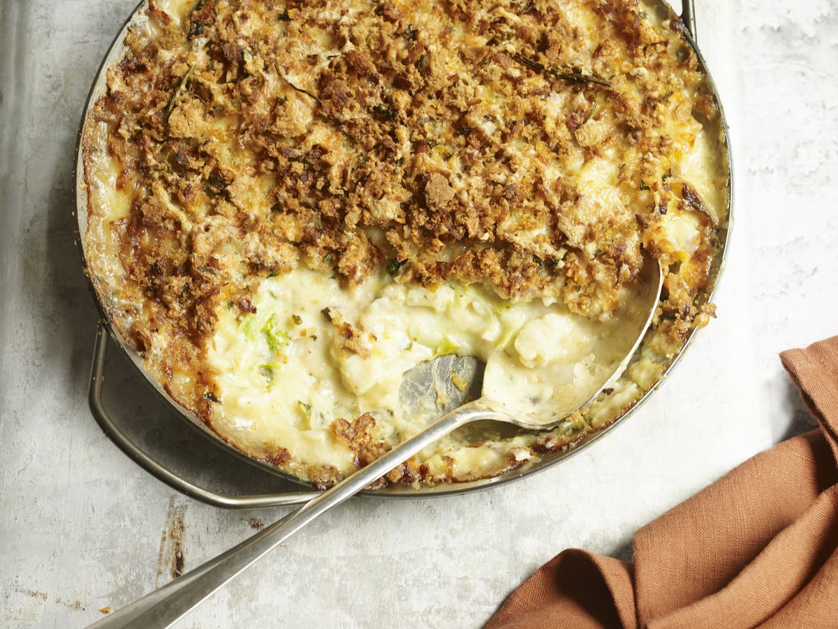 Photo looking down on a pan of cauliflower cheese gratin with a portion already spooned out.