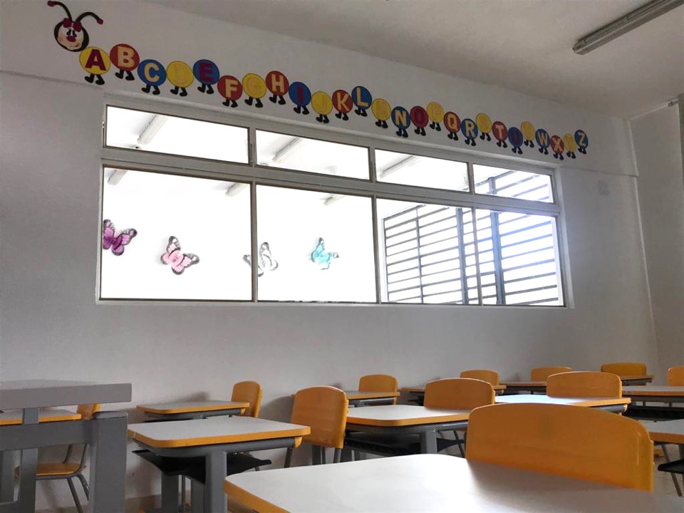 Sala de aula com paredes decoradas com o alfabeto e borboletas coloridas. 