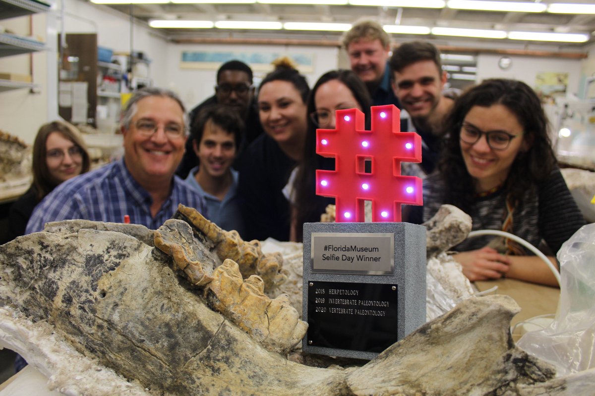group of scientists and students around a trophy and fossil jaw