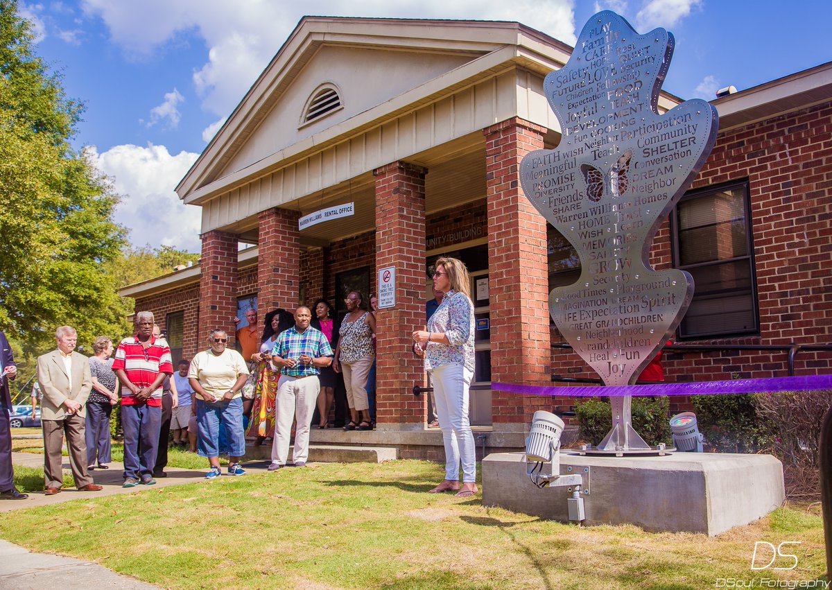 A group of people stand outside a building with a new large sculpture next to it, about to be unveiled. In the final phase of the Making Conversation with Warren Williams Homes oral history project, a 9-foot sculpture aptly named "Making Conversations" was unveiled in the community.