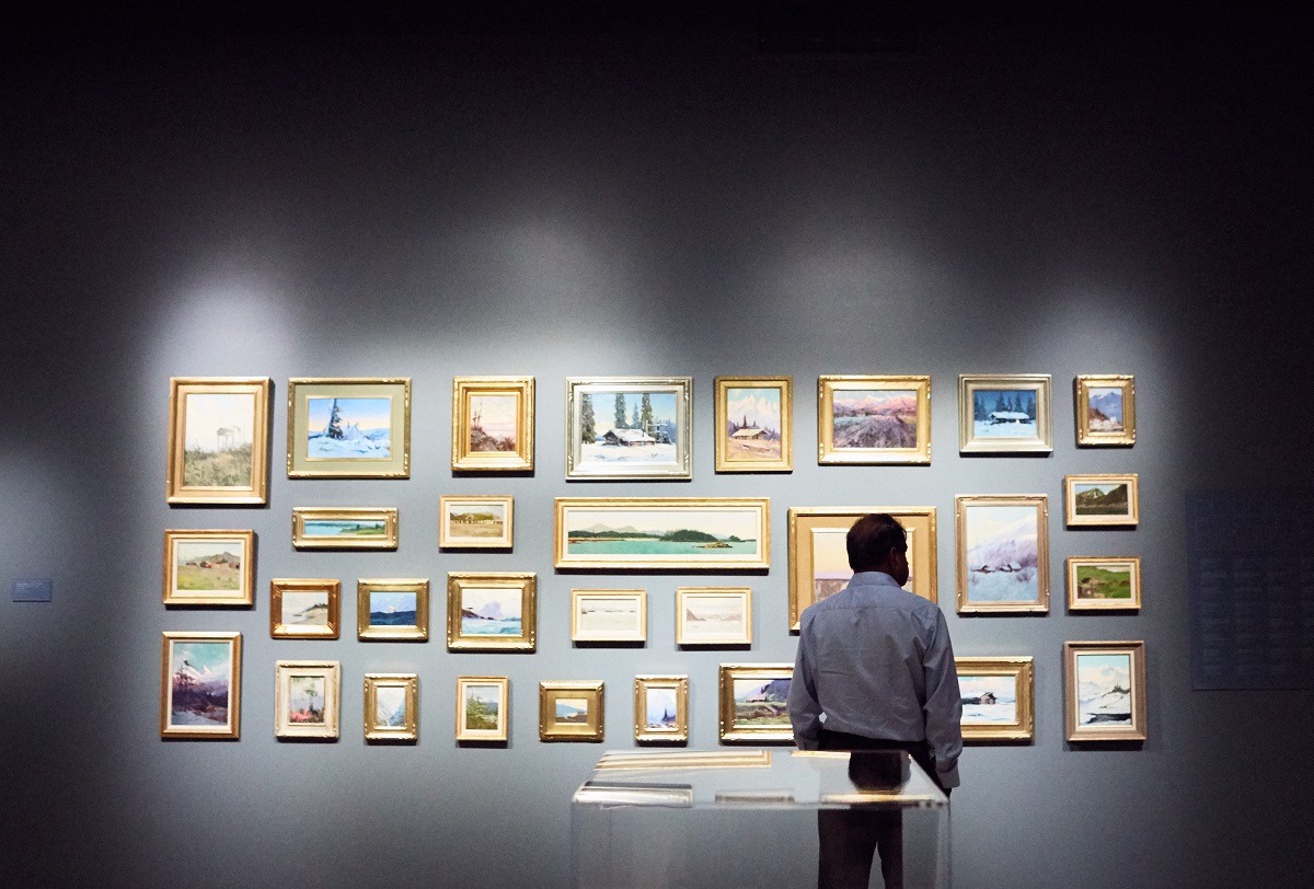 A person looking at a group of landscapes in a gallery at Anchorage Museum