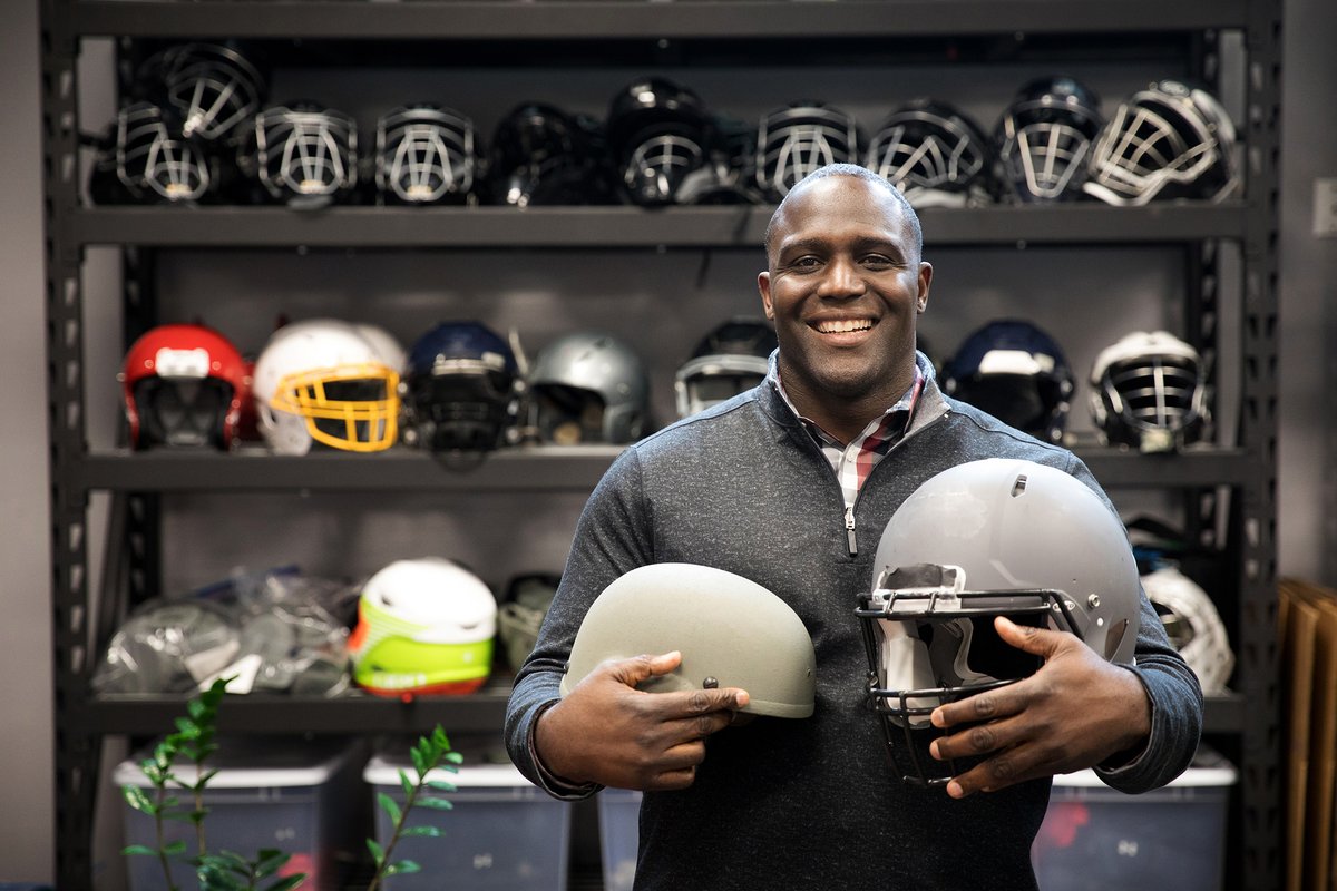 Shawn Springs holding his invention - modified helmets - in his arms