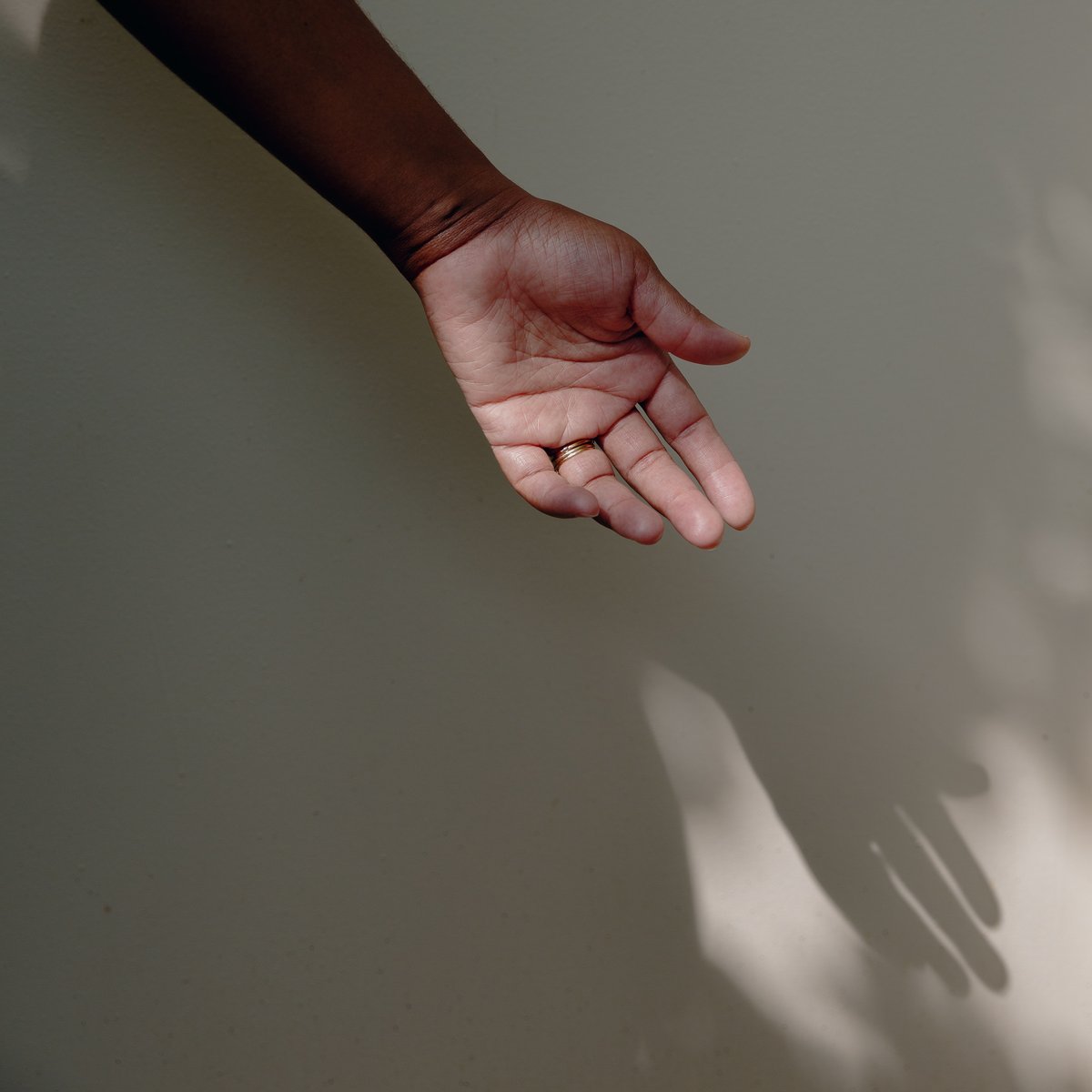 Nafeesah's hand with shadow against a white wall.