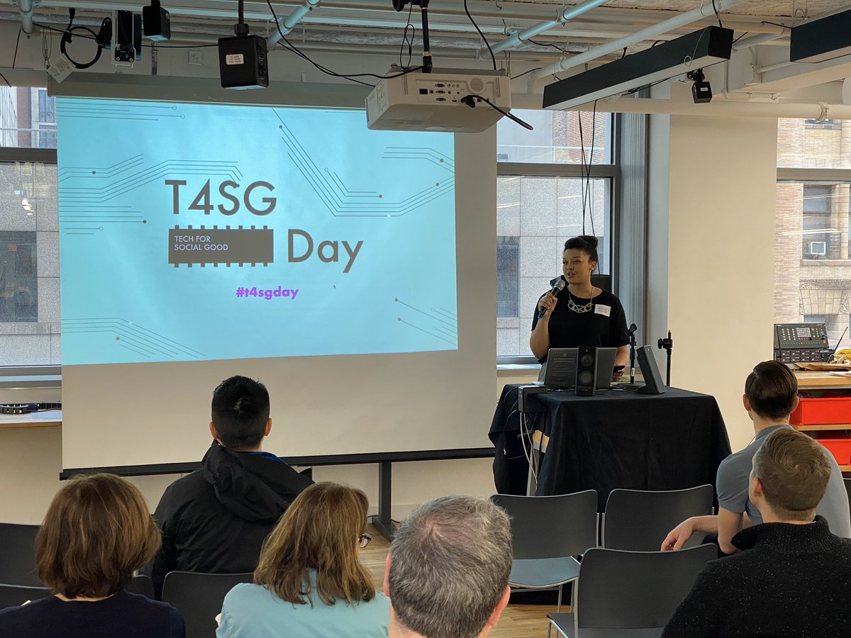 Ashely speaks at a podium with a slide behind her that says T4SG Day.
