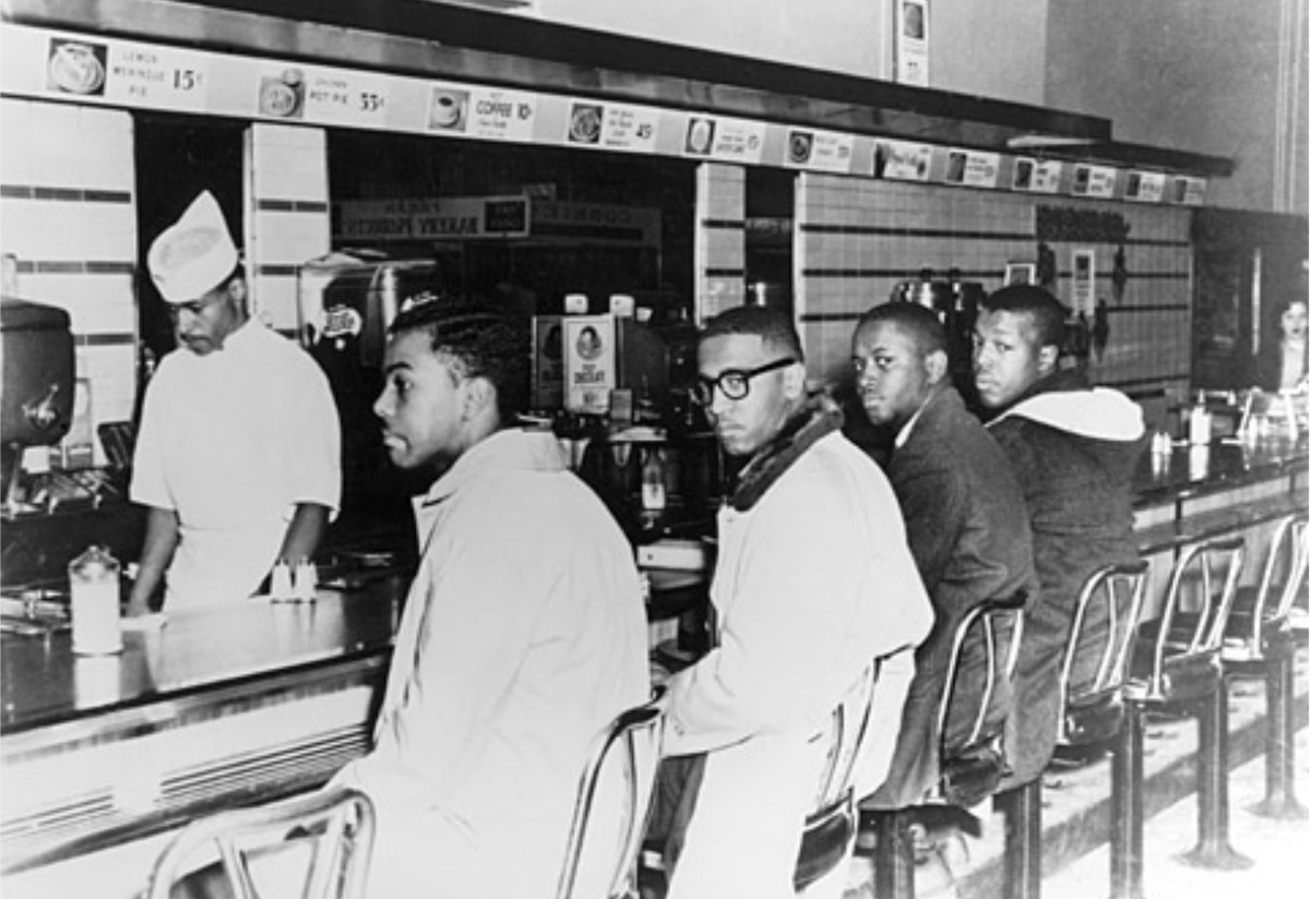 Photo from February 1960 shows Joseph A. McNeil, Franklin E. McCain, William Smith, and Clarence Henderson sitting at the Woolworth lunch counter in Greensboro, North Carolina.