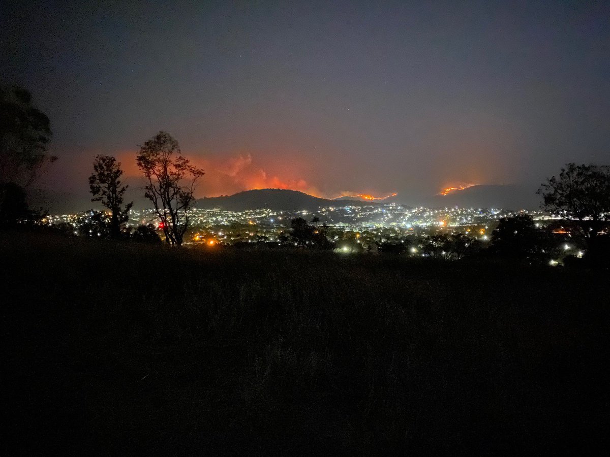 ACT_ESA's tweet photo. Residents in south CBR should expect to see active flames on the horizon. Today, several retardant drops occurred near Tharwa. Tonight, crews are strengthening containment lines with a planned backburn along Naas Rd on the east side of Mt Tennent.Please remain alert, not alarmed https://t.co/hwvQH9jmew