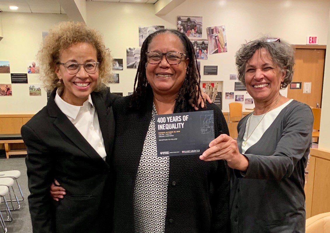 photo of smiling Linda Villarosa, Evelyn Hammonds (holding event postcard) and Mary Bassett
