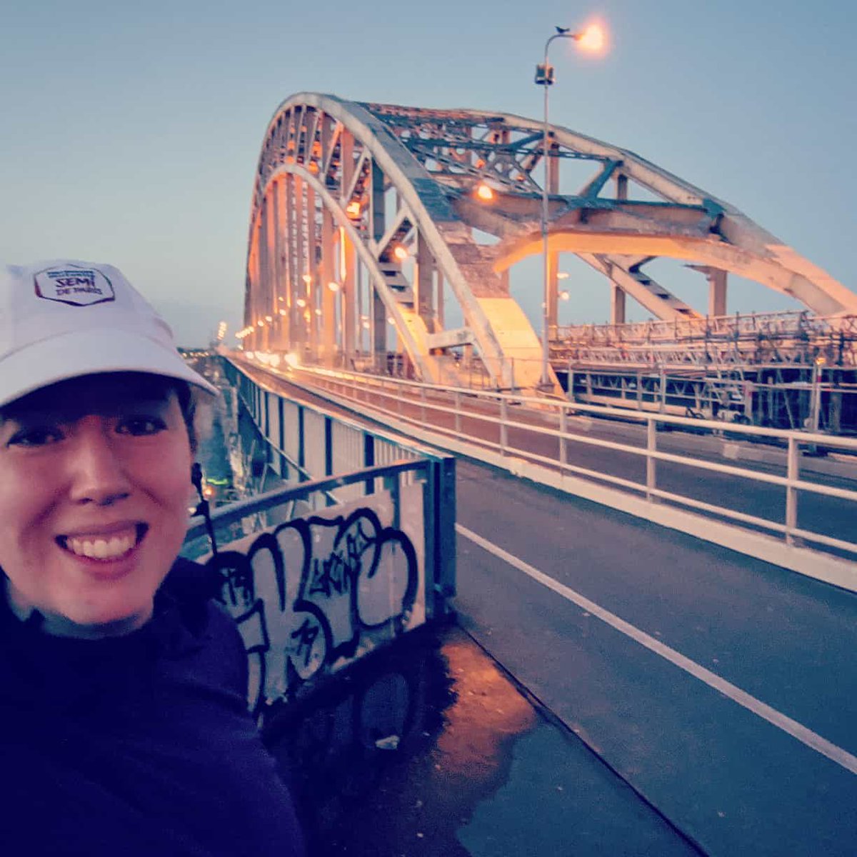 Selfie of me in running gear on a lit up bridge at dusk.