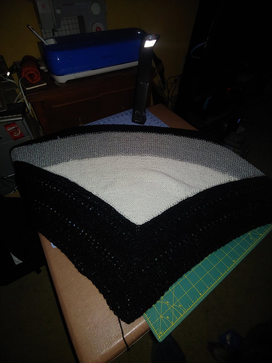 A sparkly grey white and black shawl on a card table.