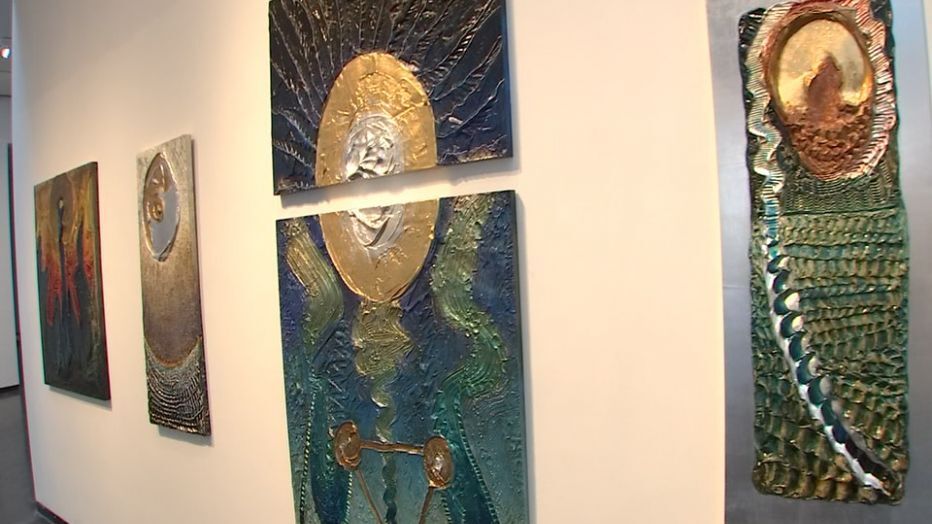 Paintings hung at waist height and available to touch at the art exhibit.