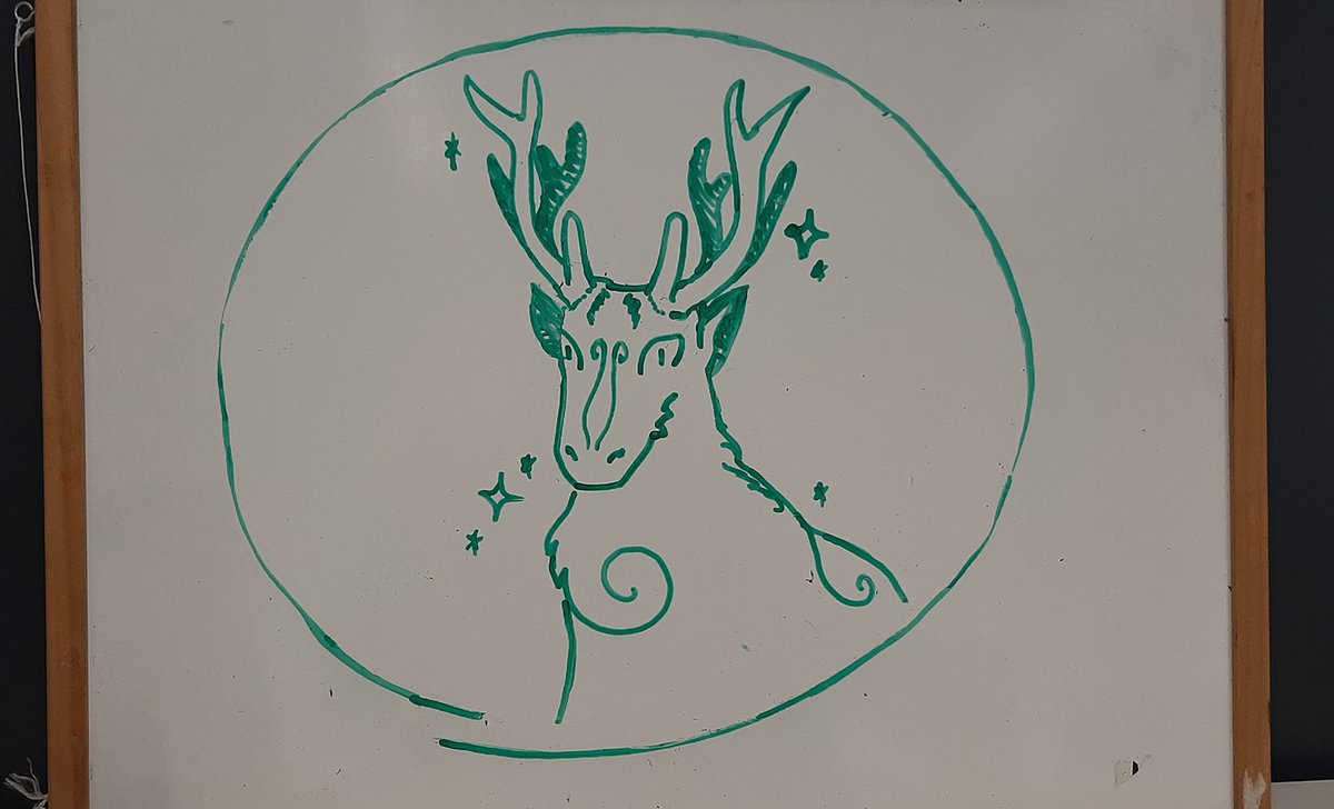 Photo of the original drawing on a whiteboard, of a sparkling deer-like creature with twirling patterns upon it's body.