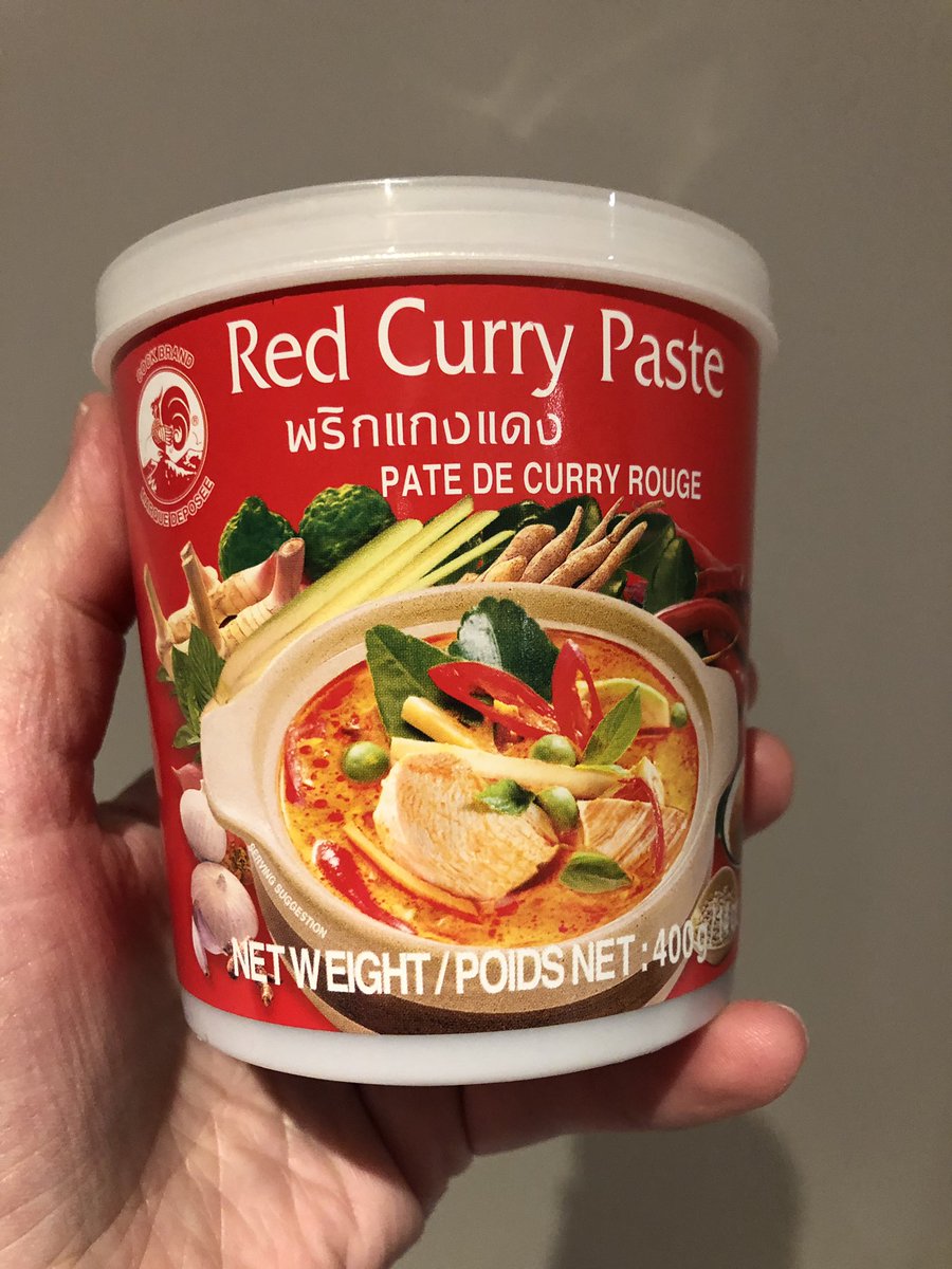 A container of red curry paste with some Thai writing on it