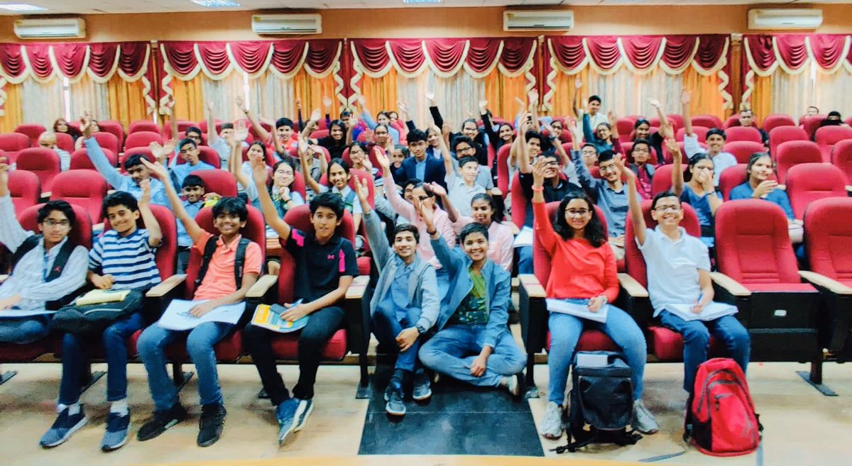 Group of young debaters all with their hands raised.