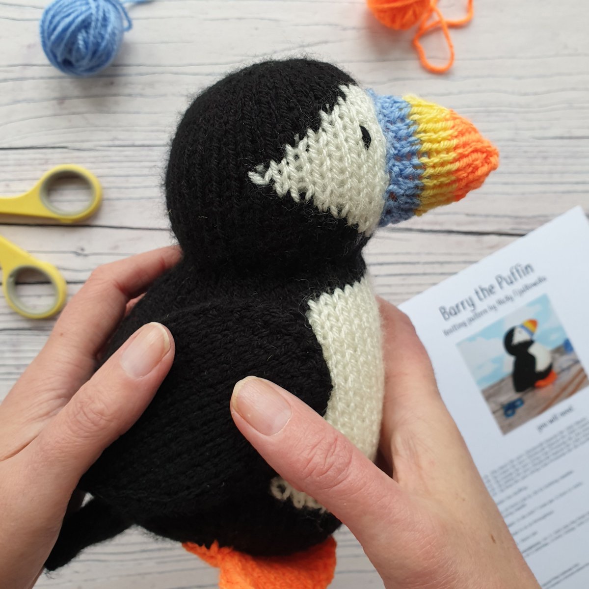 knitted puffin being picked up in two hands