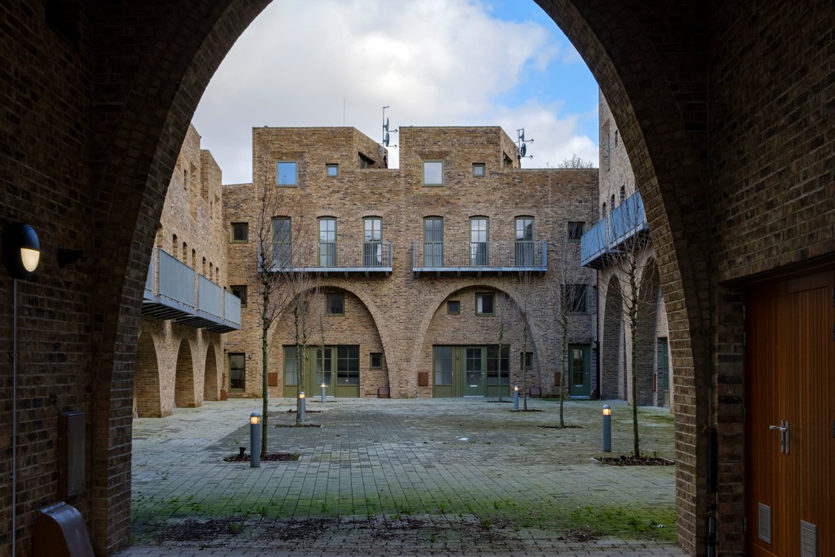 5) The houses are set around an internal courtyard, which hopefully becomes greener once residents put out some plants (Barber stresses letting residents make their homes their own). As it stands it's quite a hardscape. The courtyard is accessed through two arched gateways.