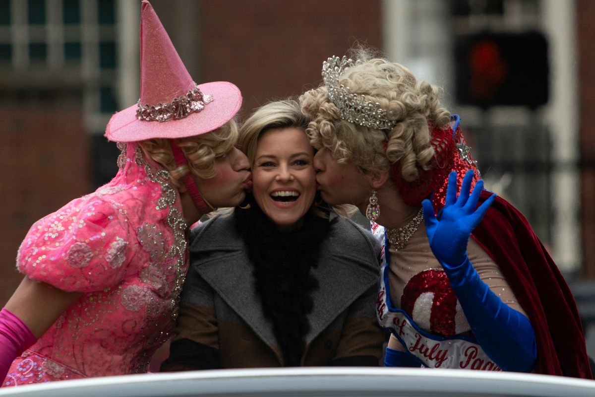 Elizabeth Banks receives a kiss on each cheek by two students