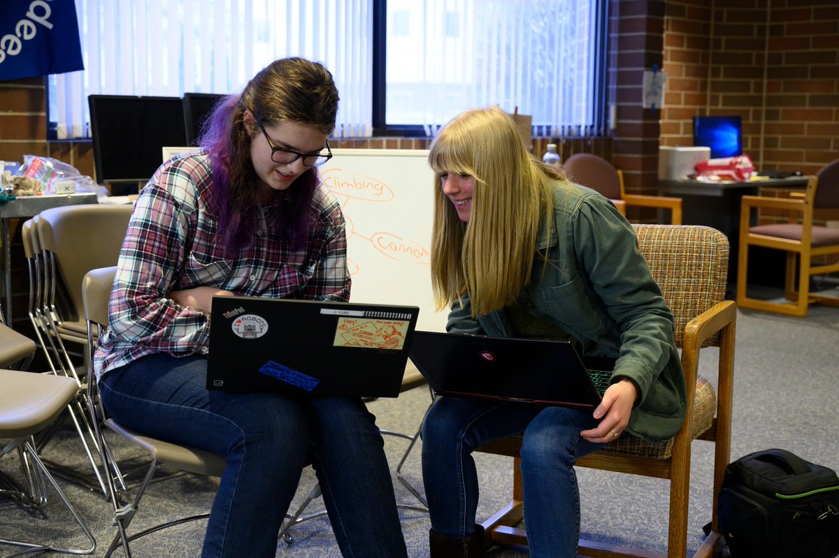 Two high school women sit with laptops