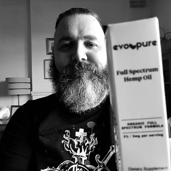 Bearded man (me) holding a card box containing a bottle of CBD oil