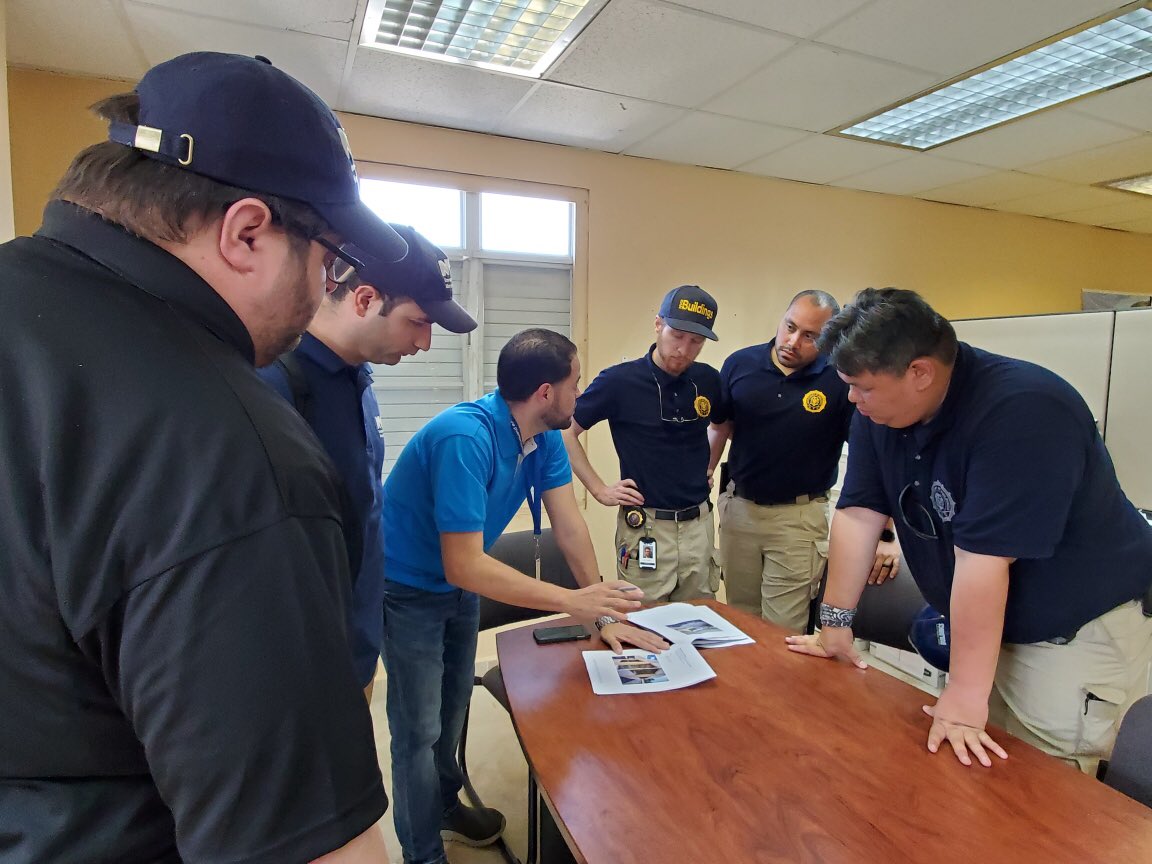 NYC Emergency Management and NYC Department of Buildings staff standing around a table with staff from City of Aguadilla in Puerto Rico.‬