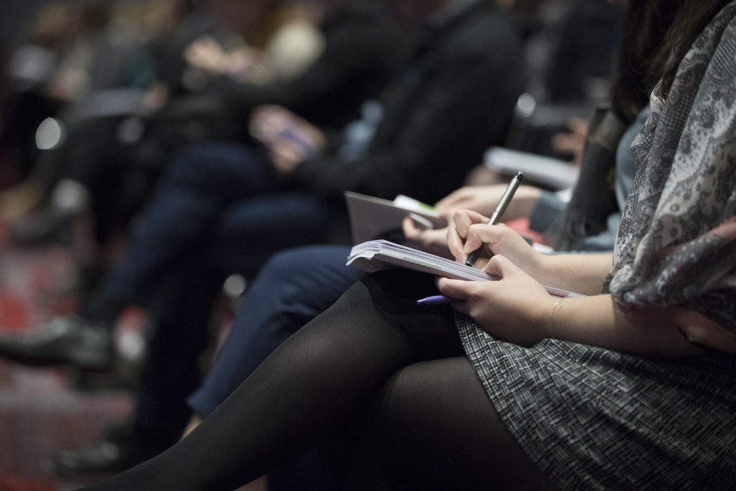 Stock image of people making notes at a conference.