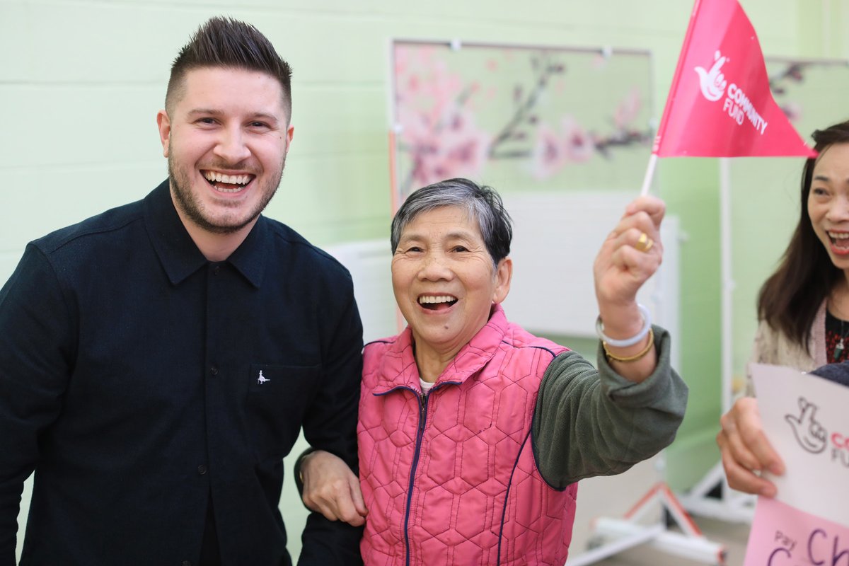 A man and a lady smiling and holding a branded flag. 